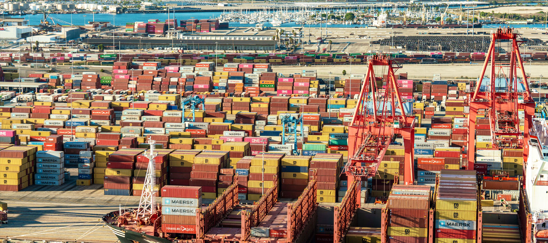 Aerial view of stacked shipping containers and cranes at a coastal California port