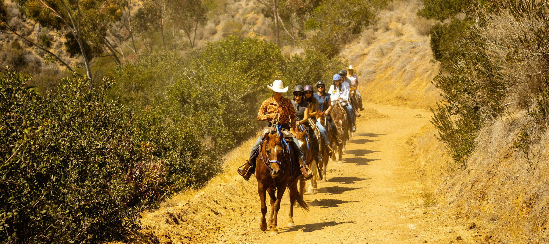 Riders in single file on a narrow canyon trail