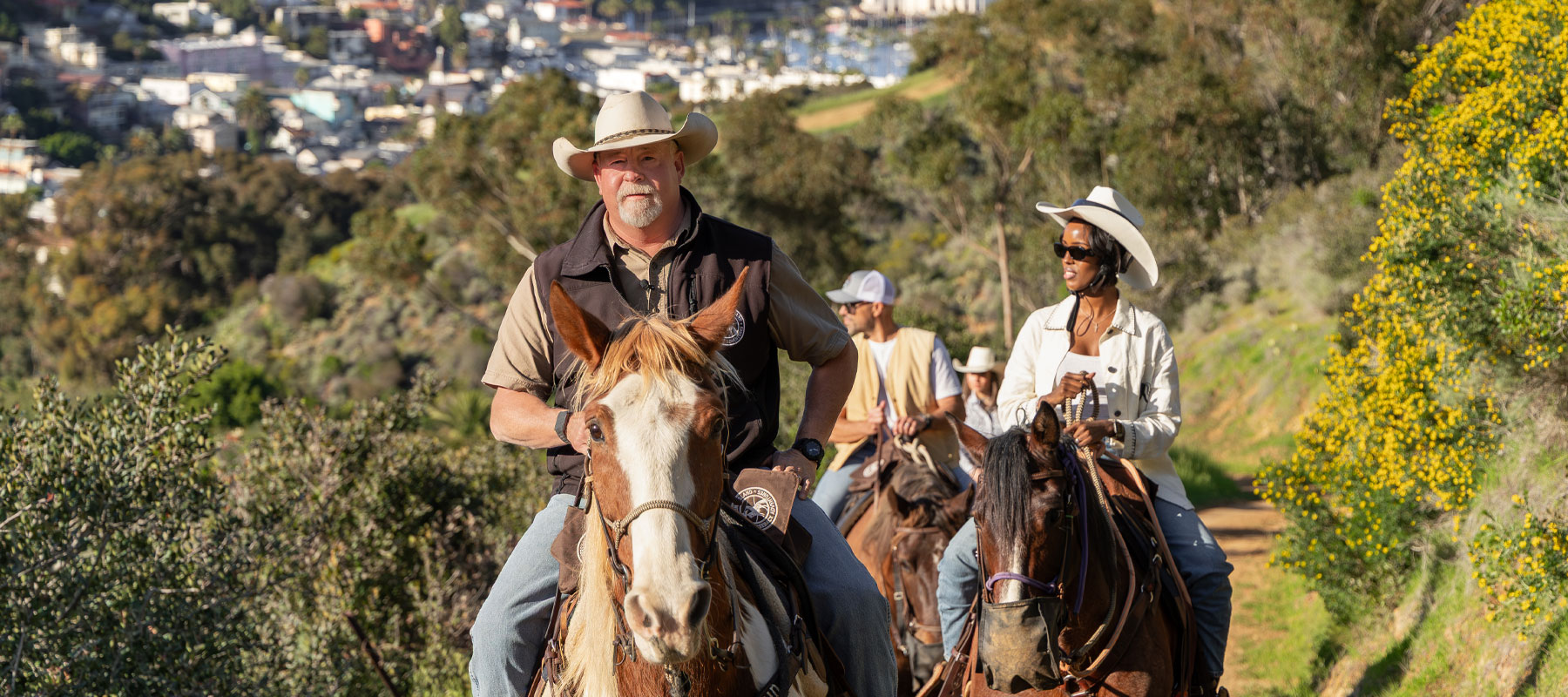 Guide leading riders on horseback with Avalon in the background