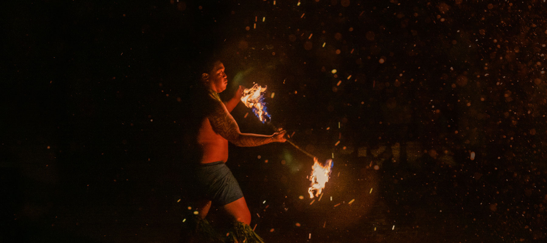 Fire knife dancer performing live during a traditional luau in Maui