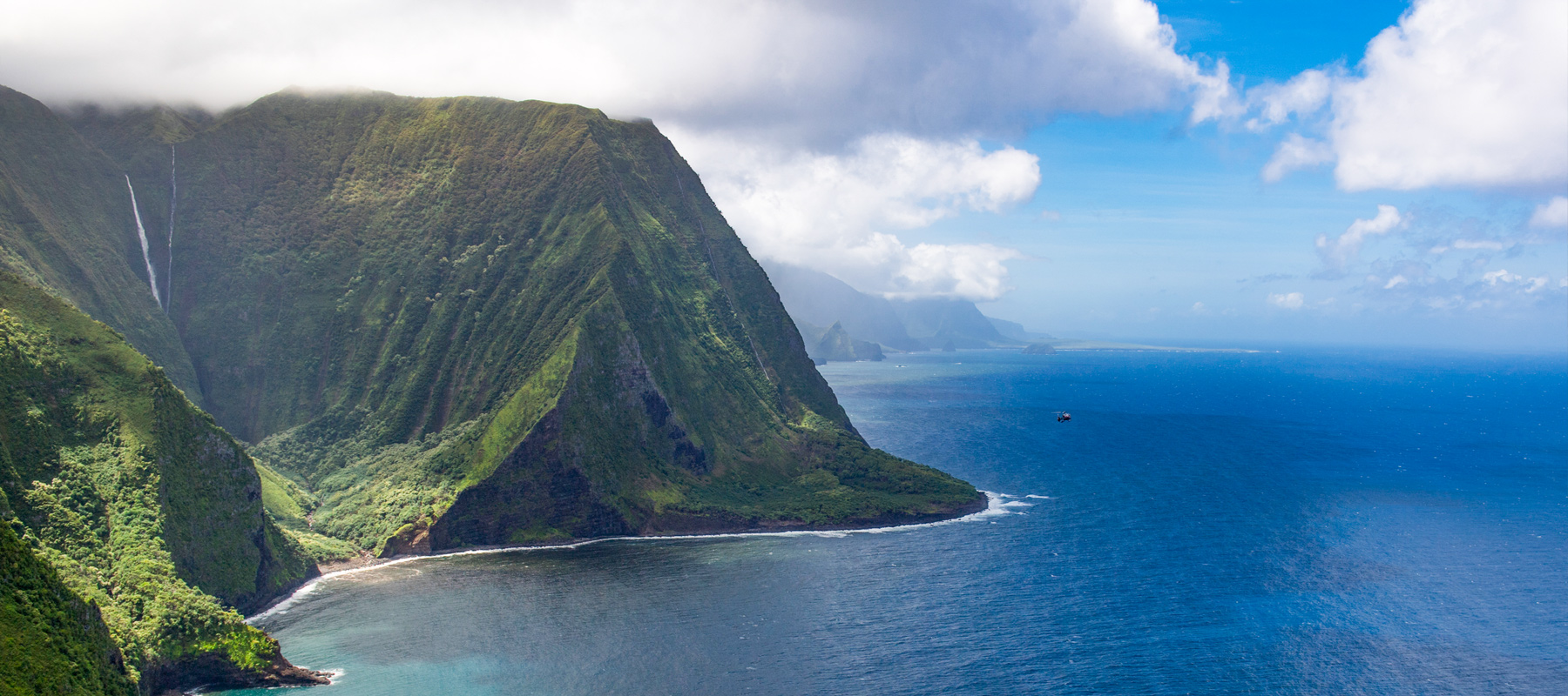 Helicopter flying past the towering sea cliffs of Molokai