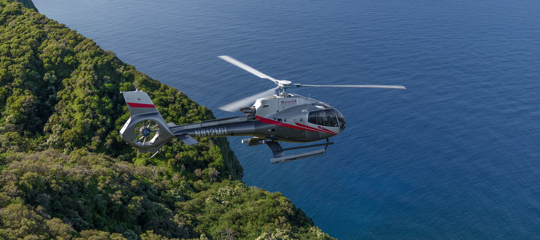Helicopter flying above the rugged coastline and Pacific waters of Molokai