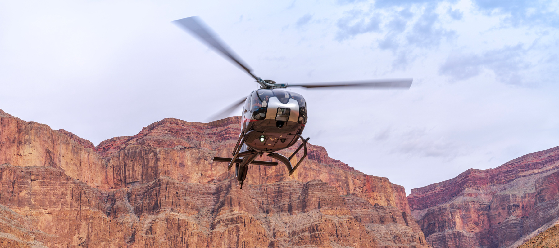 Helicopter flying above the red rock cliffs of the Grand Canyon