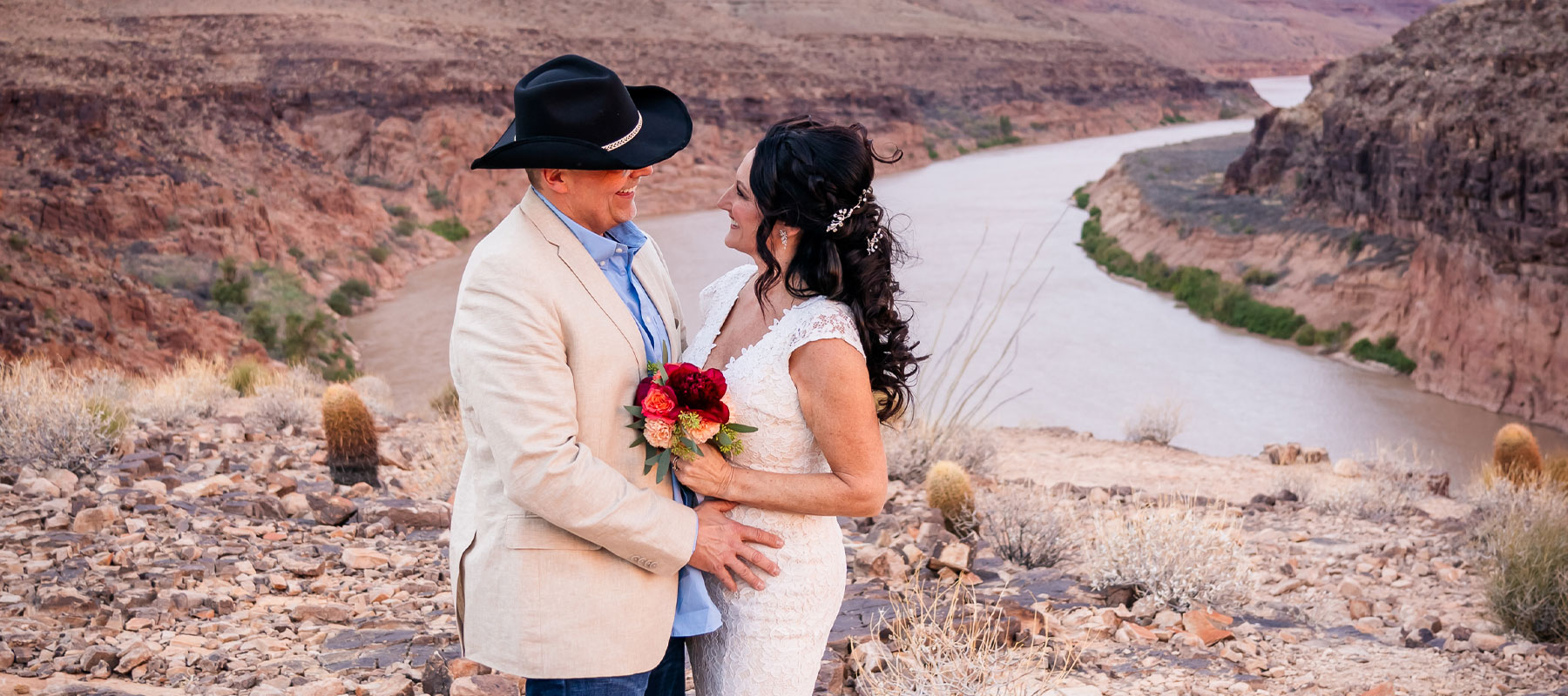 Bride and groom embracing with the Colorado River and Grand Canyon walls behind them